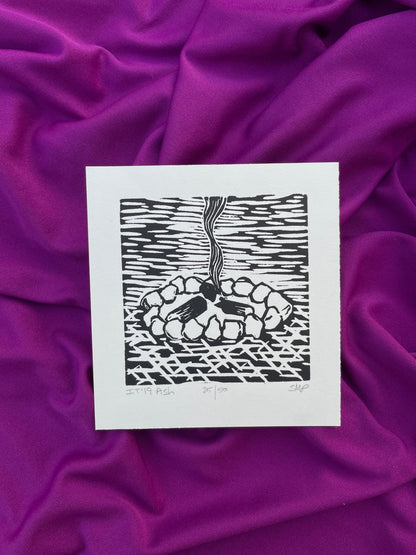 Stylized print of smoldering campfire. Rocks surround three logs with smoke wisps traveling up. Created with printmaking method of linocut relief. Small decor for outdoorsy people.